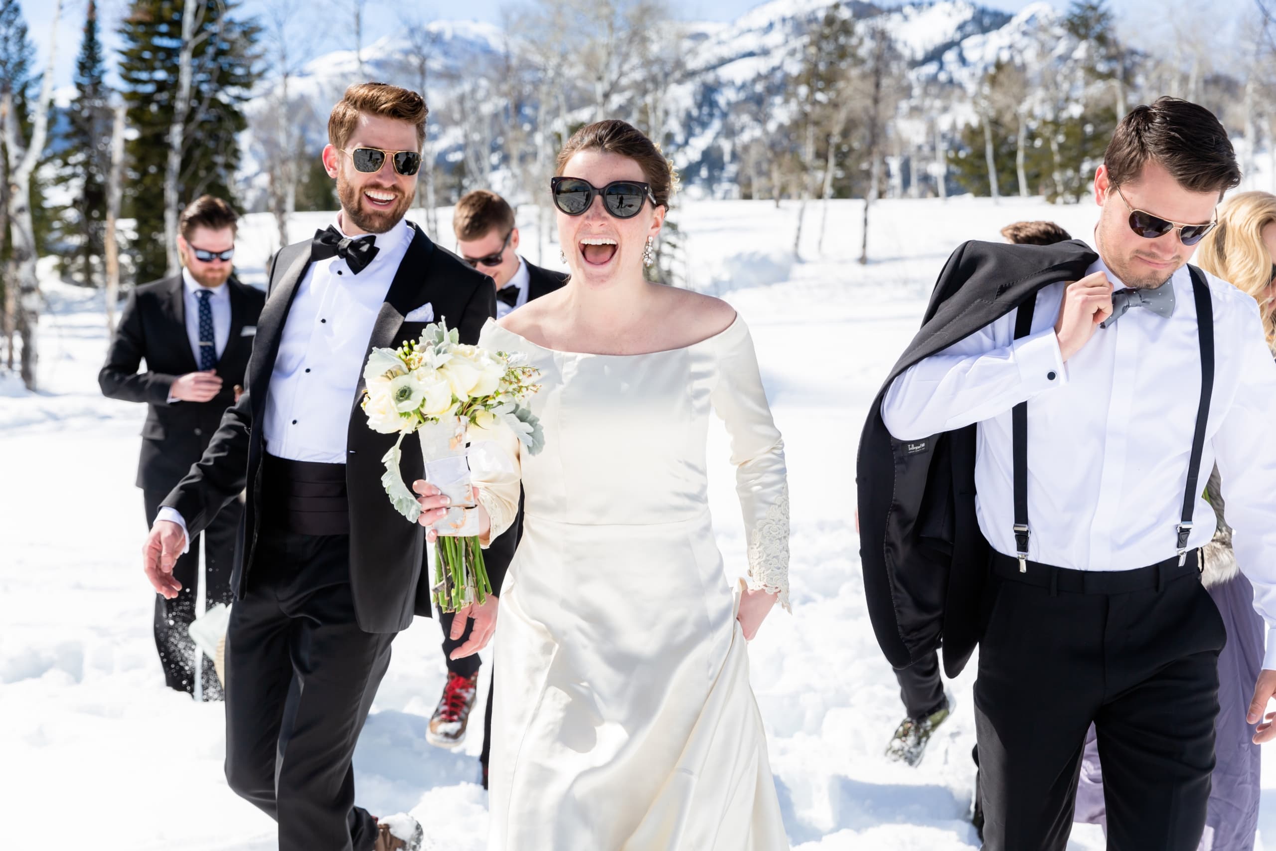 A wedding party tramping through snow on a sunny day