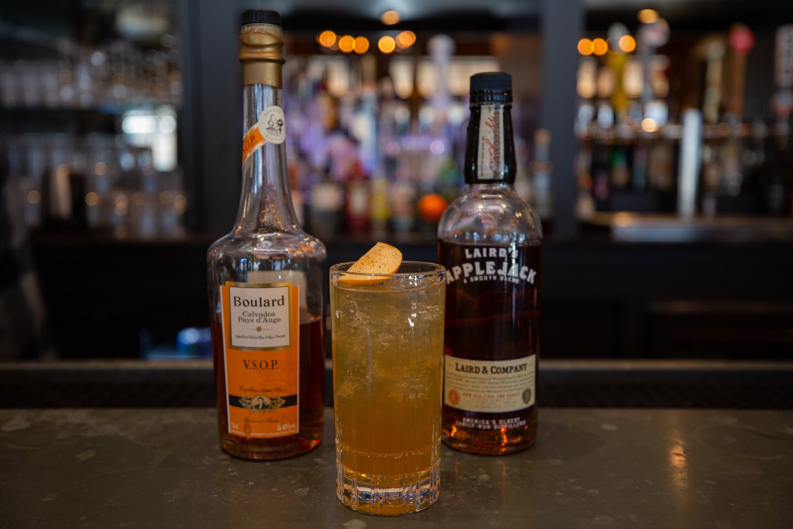 bottles of alcohol and a cocktail on a bar top