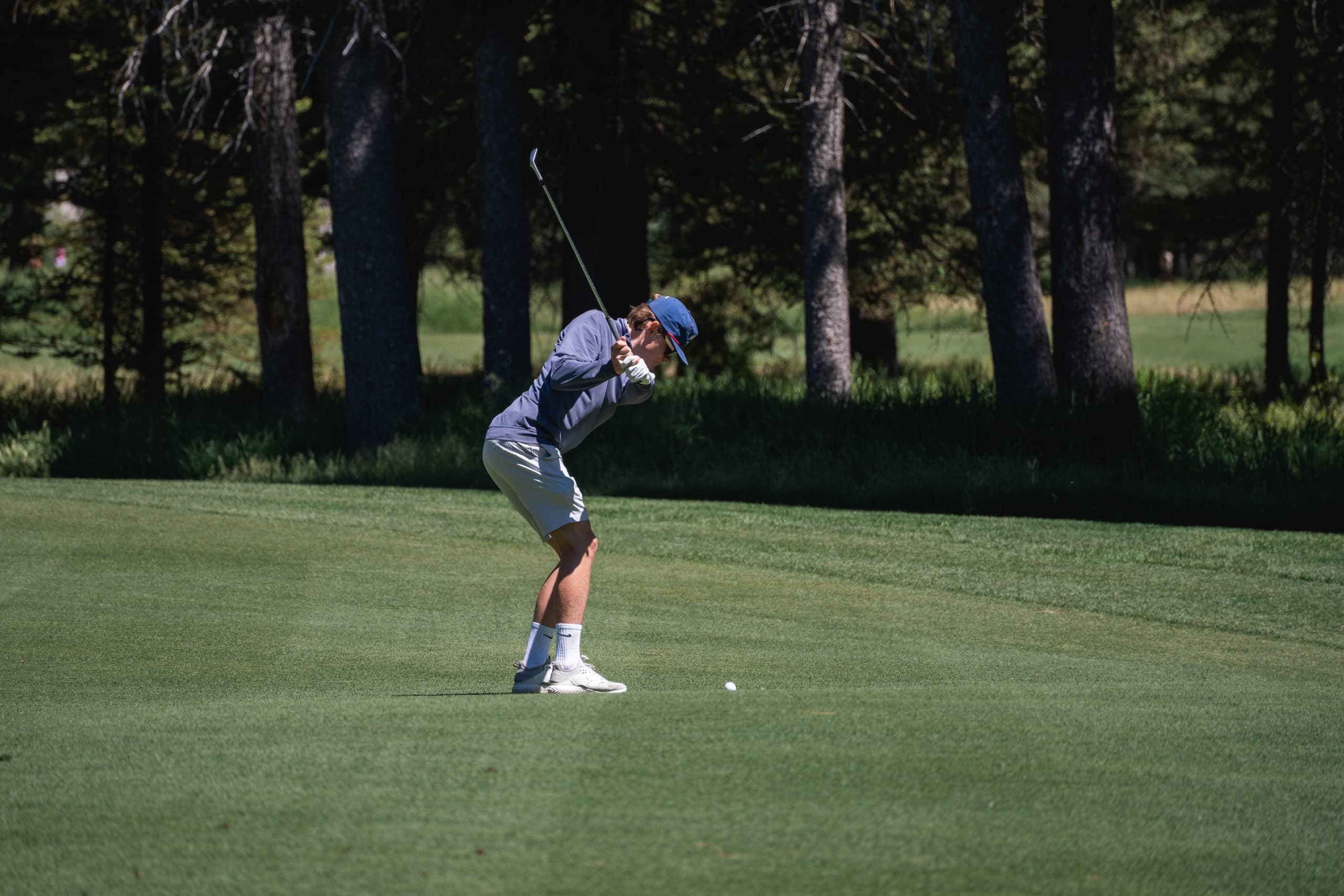 A golfer captured mid swing, focused on hitting their golf ball