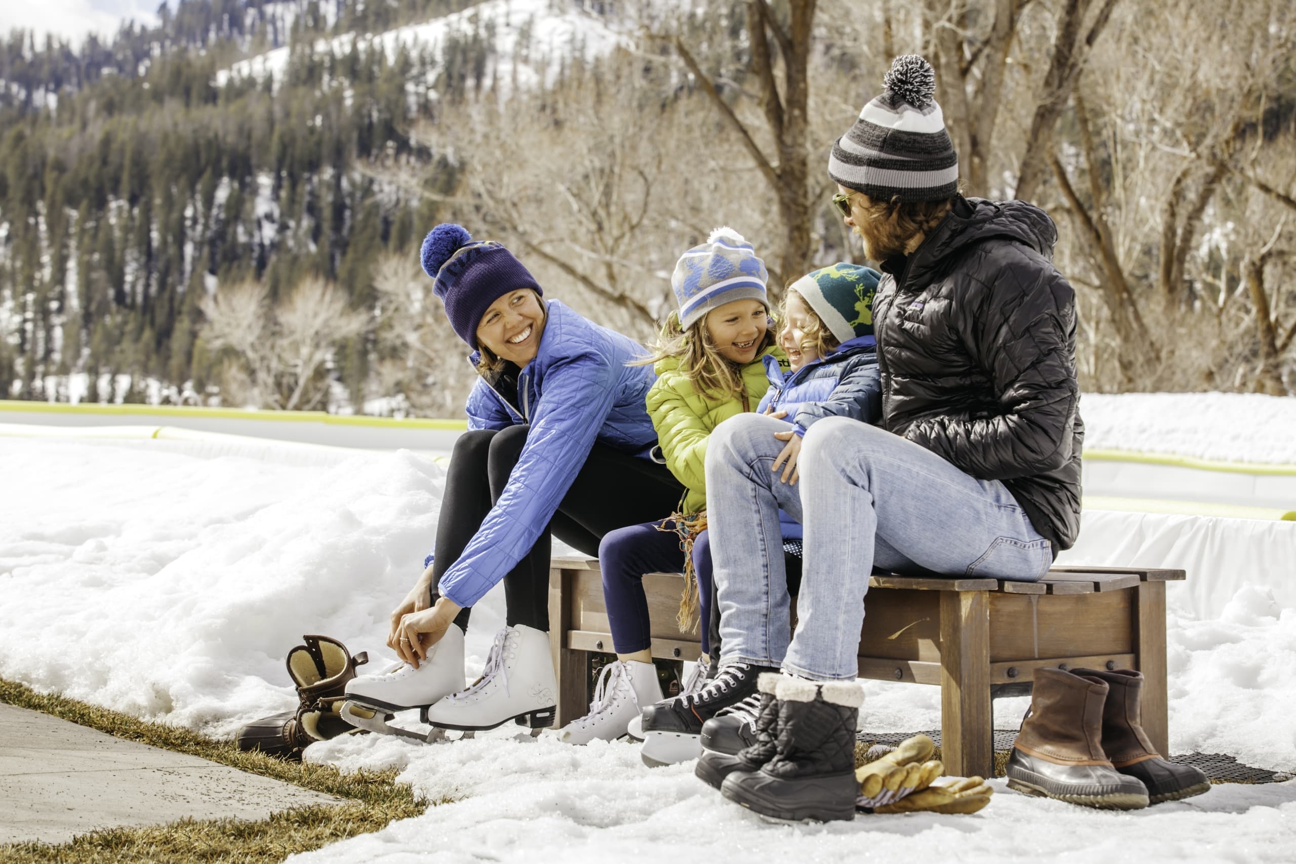 A family with two young children snow ice skating outdoors in Jackson Hole, WY.