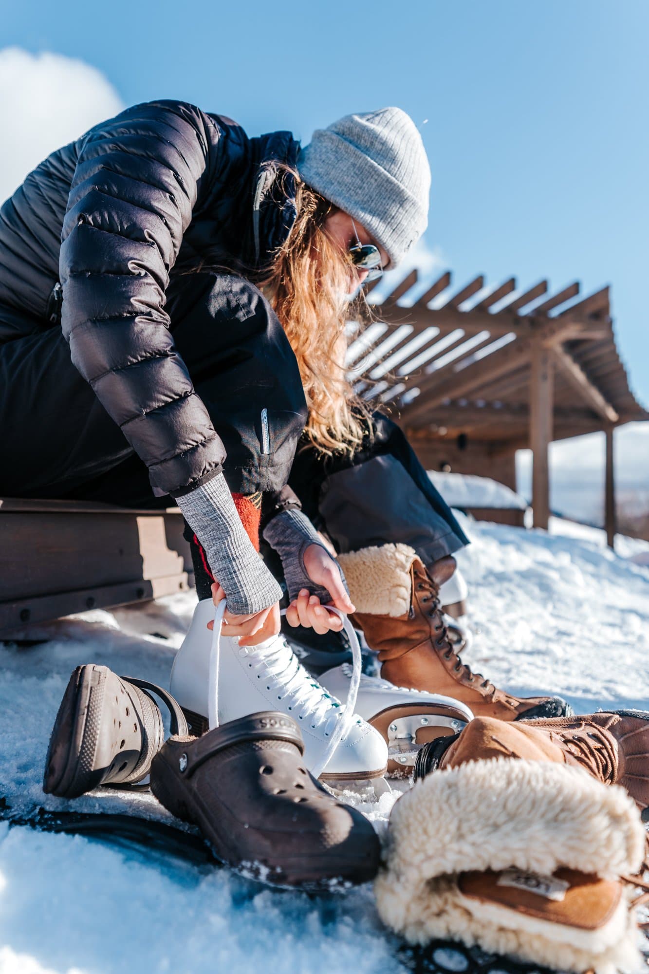 Woman lacing up to ice skate outdoors