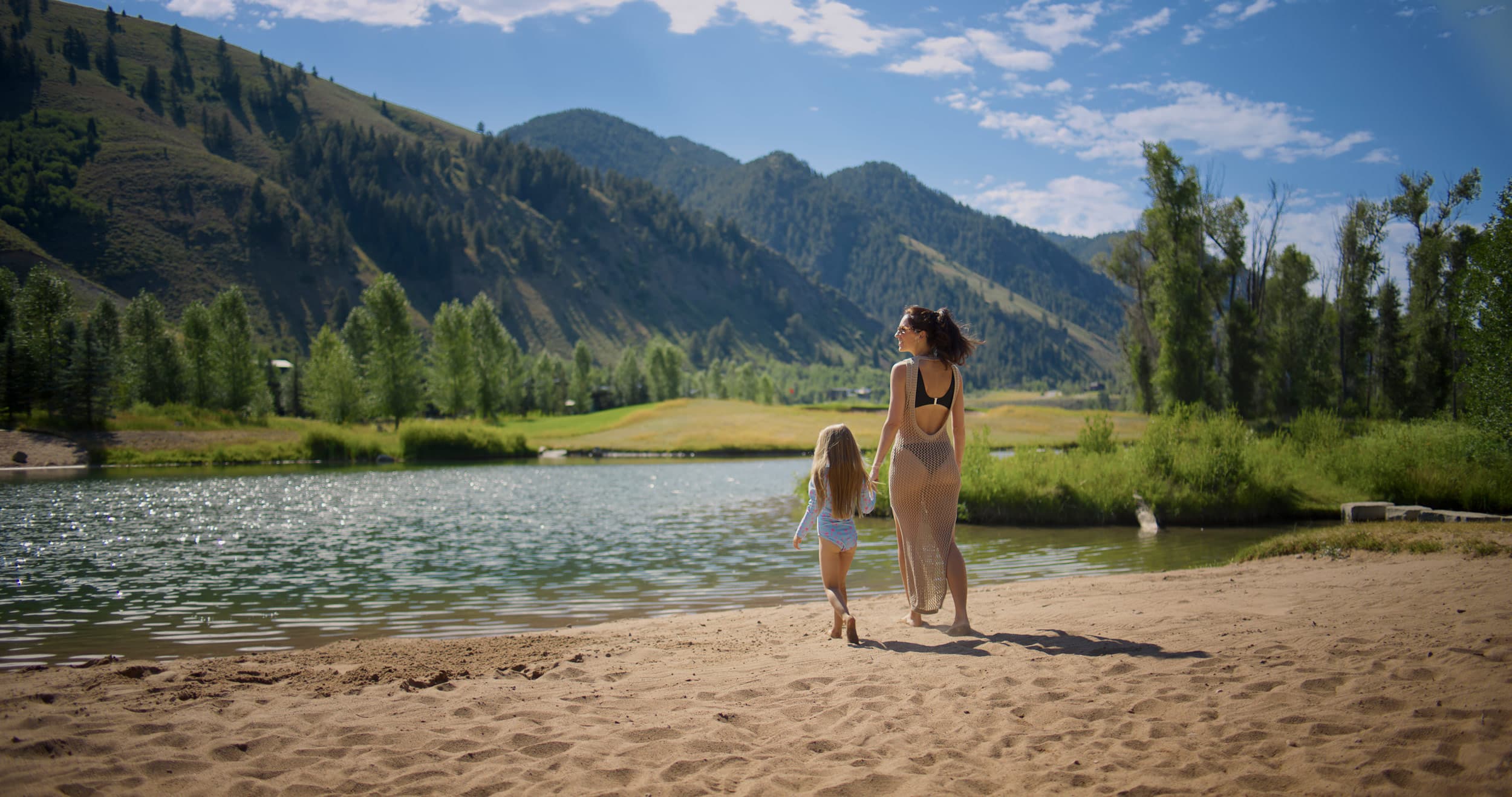 Mom And Daughter On The River Beach