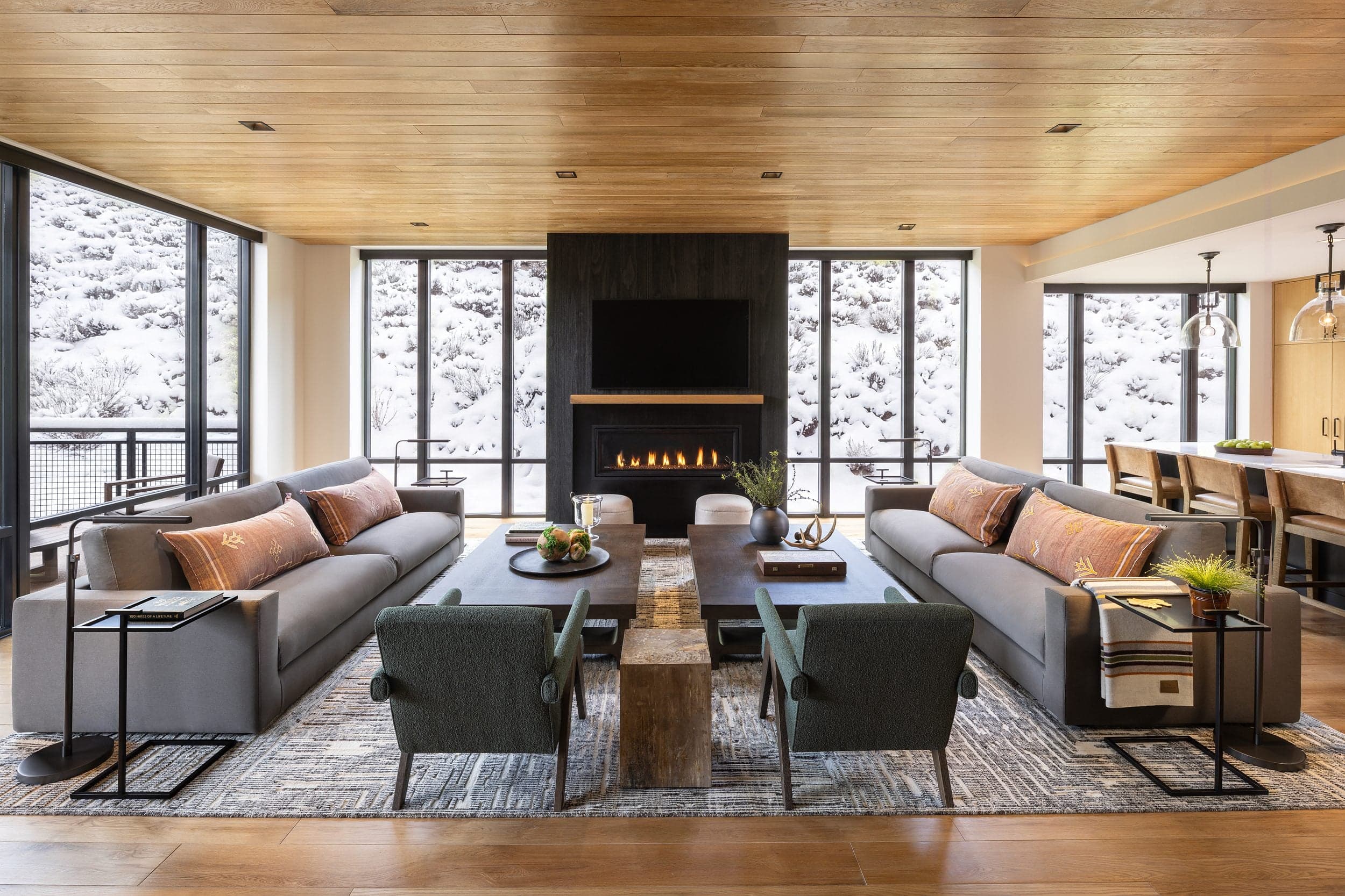 Luxury penthouse living room at Snake River Sporting Club in Jackson Hole, Wyoming, with a fireplace, floor-to-ceiling windows and snowy winter views