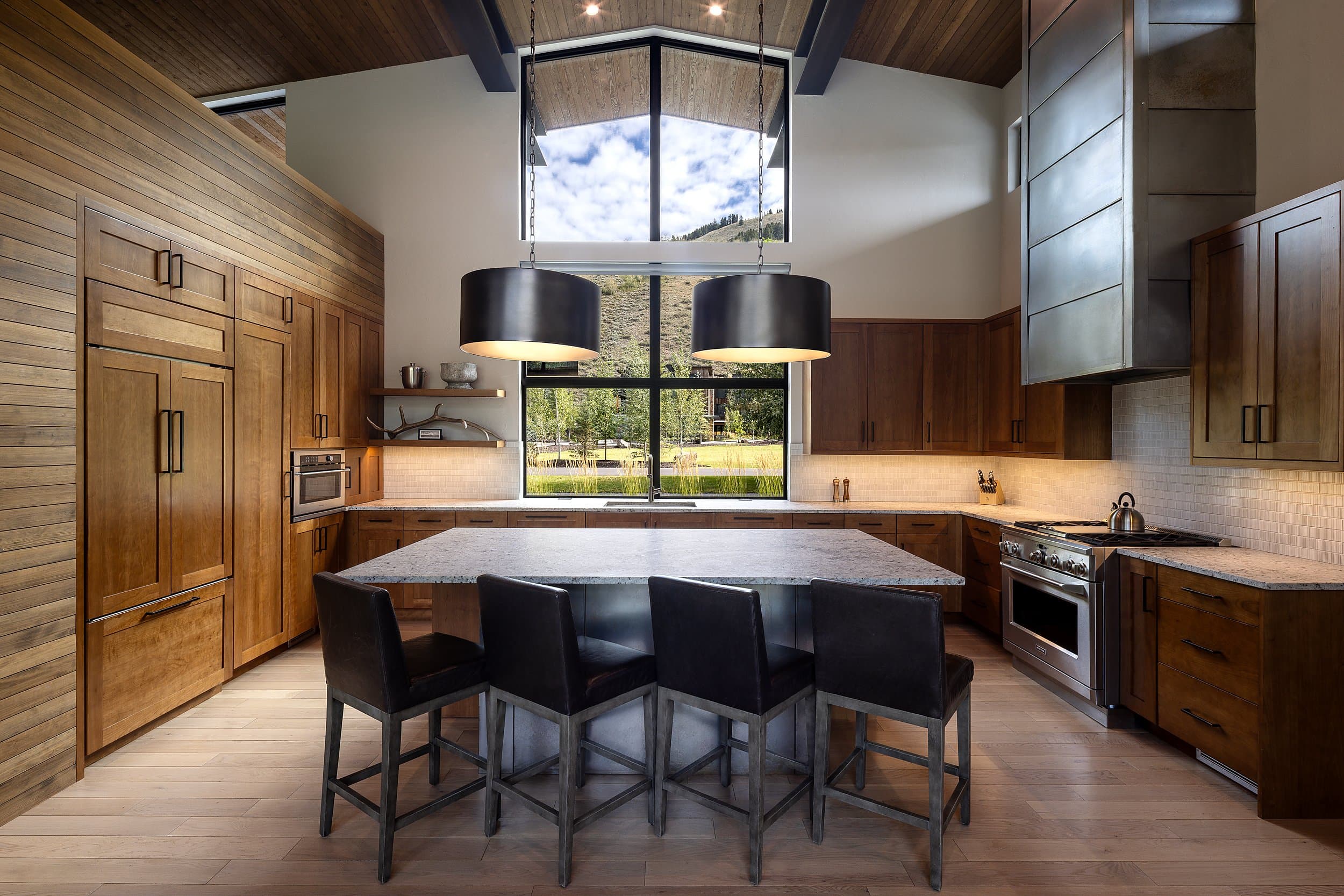 Chef's kitchen with a granite island, leather barstools and mountain-view windows at Snake River Sporting Club in Jackson Hole, Wyoming